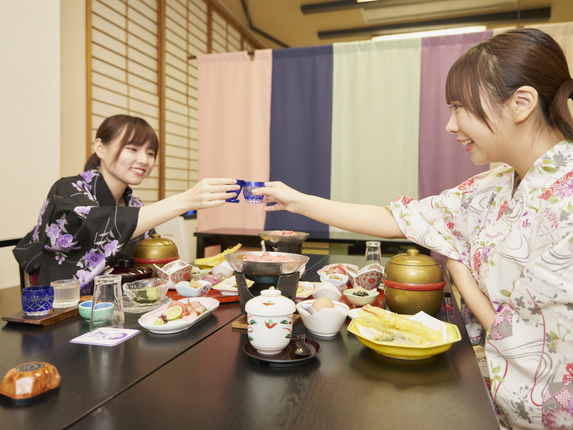 Huéspedes relajándose con un té en una habitación de Tofuya Ryokan