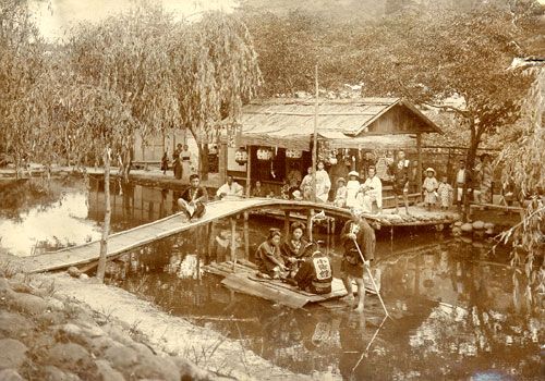 Orang-orang menikmati naik perahu di kolam di Onogawa Onsen tempo dulu