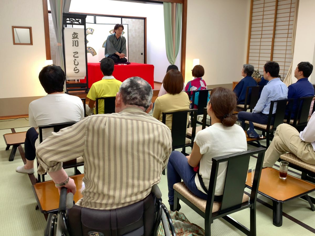 Pertunjukan rakugo di ruang makan Tofuya, dengan seorang tamu berkursi roda di antara penonton